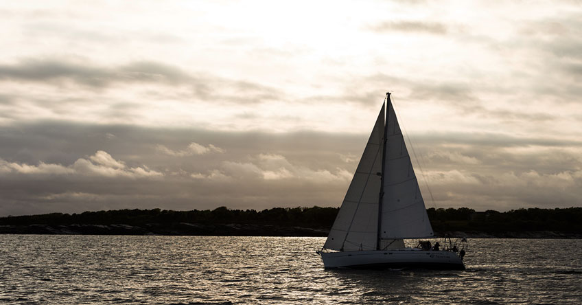A cruising sailboat sailing at dusk